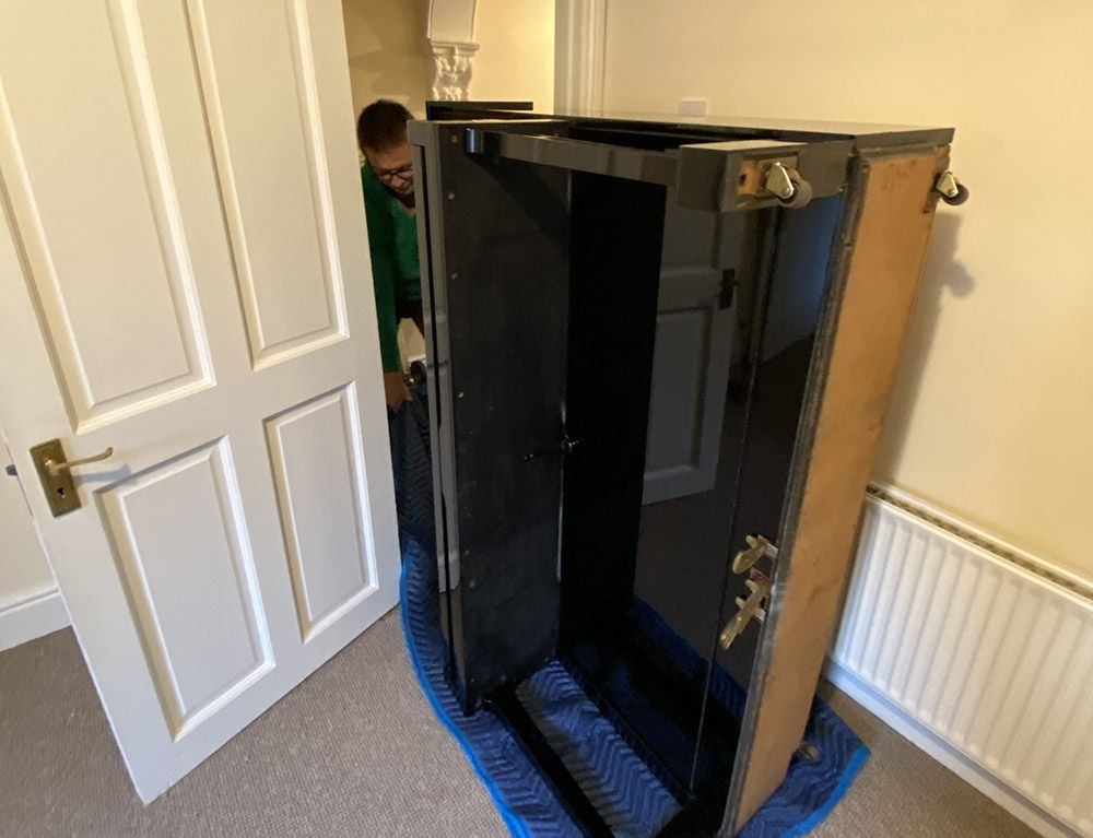 Traslocatore di pianoforti che cerca di far passare un pianoforte da un porta stretta